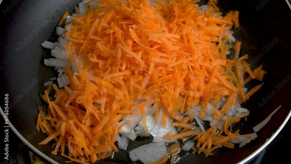 Freshly grated carrots and onions are fried in a pan. Close-up. Slow motion video. Cooking master class. Home cooking. Freshly grated carrots and onions are fried in a pan. Close-up. Slow motion video. Cooking master class. Home cooking.