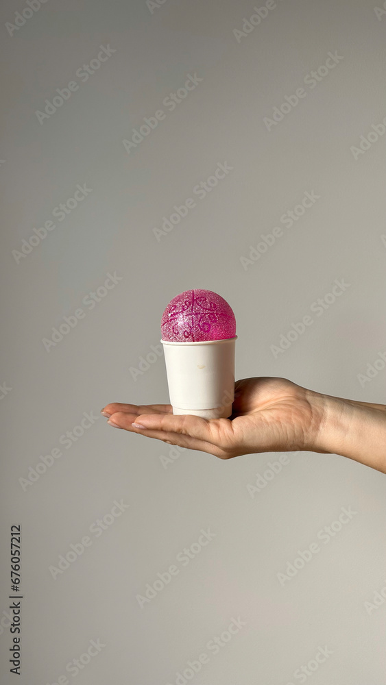 A woman is holding a white paper cup with Christmas balls like ice cream in her hands. New Year layout concept. A woman is holding a white paper cup with Christmas balls like ice cream in her hands. New Year layout concept.