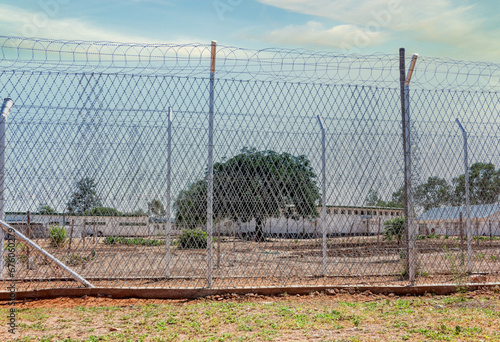 generic view of a prison fence with razor wire and barber wire rolls in top exterior yard