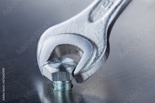 Wrench tightens bolt in steel billet. Spanner, bolt, screw and nuts.