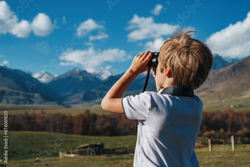 Boy with binoculars in the mountains looking into the distance