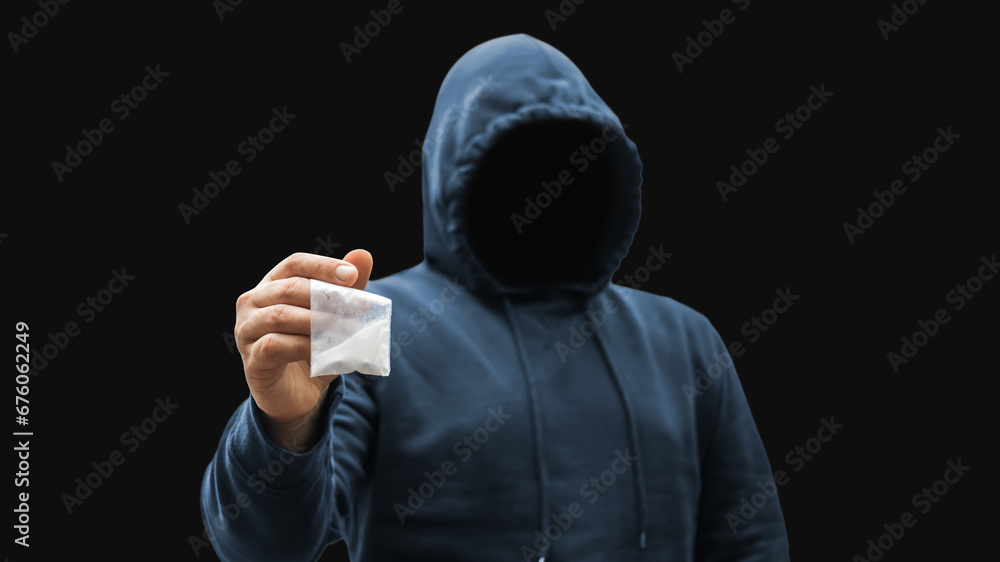 Faceless man in a hood holds transparent plastic bag with white powder hard drugs on dark background, anonymous drug dealer or gangster sells narcotics - obrazy, fototapety, plakaty 