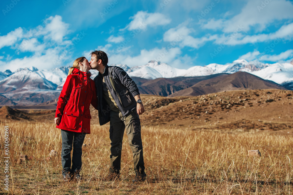 Happy young couple kissing on mountains background in autumn