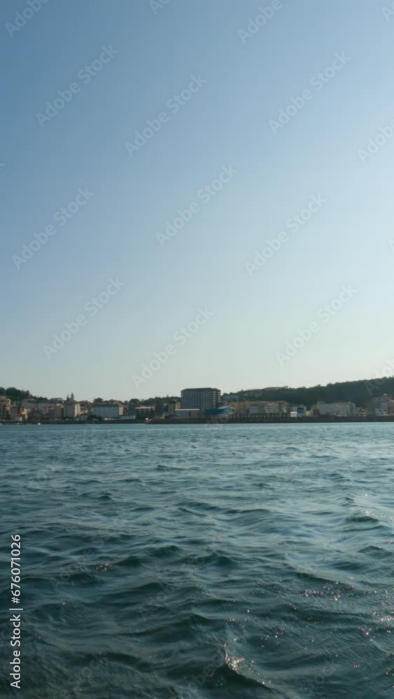 Slow-motion capturing Santa Uxía de Ribeira as a boat gracefully glides past its harbor and waterfront on a clear, sunny summer afternoon. Slow-motion capturing Santa Uxía de Ribeira as a boat gracefully glides past its harbor and waterfront on a clear, sunny summer afternoon.