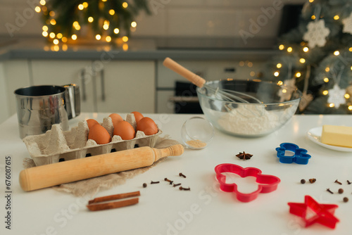 On the kitchen table there is a bowl with flour, a whisk, spices and molds for making Christmas cookies