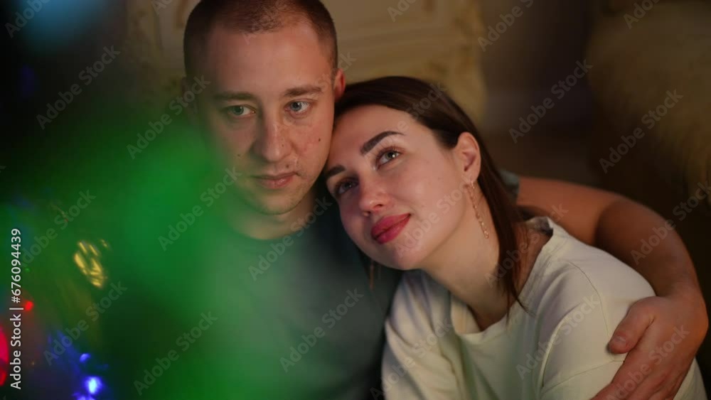 Slow motion couple in love. Close-up of a tender embrace in a romantic atmosphere near a Christmas tree. The woman pressed herself close to the man and laid her head on his shoulder. The man put his Slow motion couple in love. Close-up of a tender embrace in a romantic atmosphere near a Christmas tree. The woman pressed herself close to the man and laid her head on his shoulder. The man put his