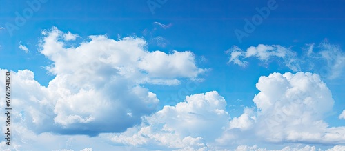 The bright blue sky on a summer day adorned with fluffy white clouds adds to the beauty of nature s backgrounds and showcases the contrasting overcast weather outdoors