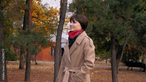 Woman with smile walks through city park to meeting with entrepreneur in autumn