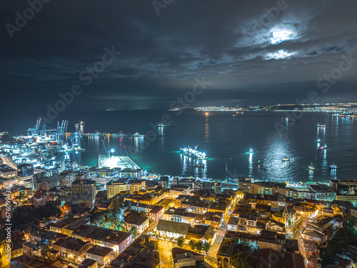 Vista aérea noturna da região do Terminal Pacífico Sur Valparaíso com lua cheia escondida entre nuvens e barcos ao redor. photo