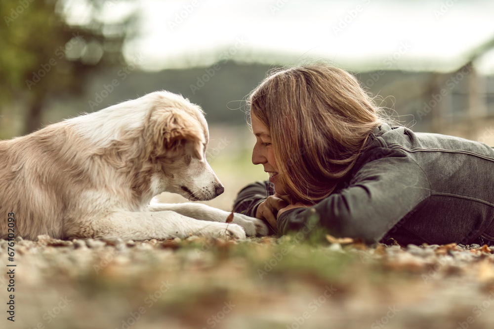 A young woman and her border collie puppy dog cuddling and interacting together in autumn outdoors, dog and owner concept