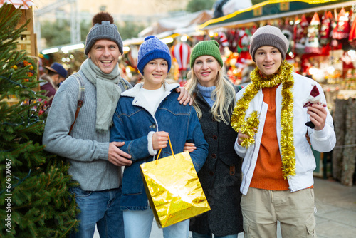 Cheerfull family with two teenagers posing with christmas gifts at Xmas market