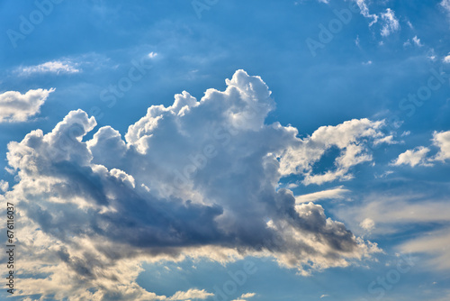 Expansive blue sky with textured clouds, casting shadows and light, depicting nature's dynamic beauty.