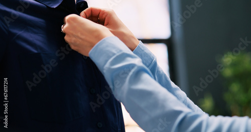 Worker arranging shirt on mannequin, checking stylish merchandise in modern boutique. Caucasian employee working at store visual, looking at hangers full with new fashion collection in shopping mall