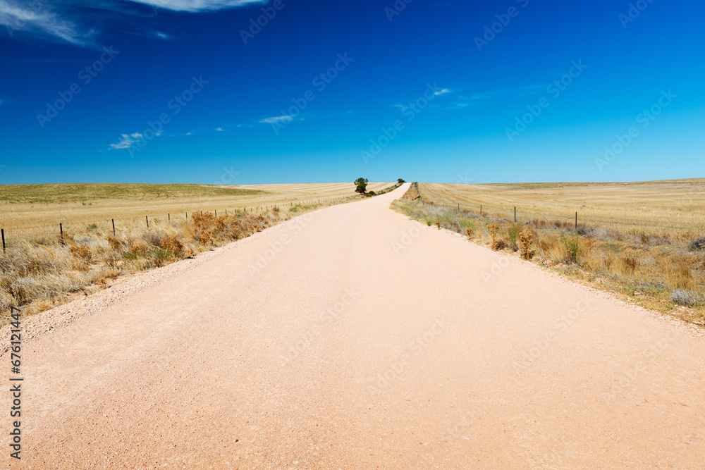 Dirt road in the country stretches into the distance under a blue sky in South Australia