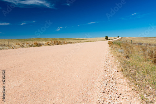 Dirt road in the country stretches into the distance under a blue sky in South Australia