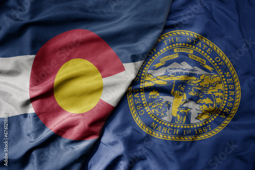 big waving colorful national flag of nebraska state and flag of colorado state .