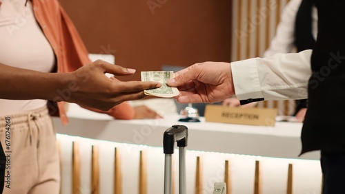 Foto Close up of thankful hotel guest tipping helpful bellboy after receiving great customer service