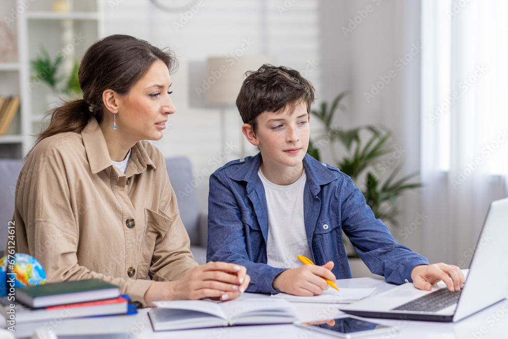 Mother and son studying together sitting at desk at home in living room, boy and woman tutor teaching at home, doing homework together Mother and son studying together sitting at desk at home in living room, boy and woman tutor teaching at home, doing homework together