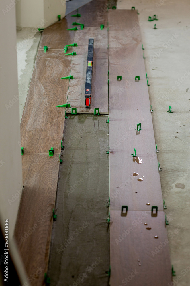 Tile levelling system, four plastic green clips with wedges. Close-up view, selective focus, blurred background Tile levelling system, four plastic green clips with wedges. Close-up view, selective focus, blurred background