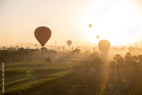 hot air balloons floating over dusty desert villages in luxor egypt during sunrise