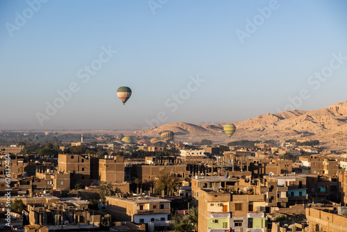 hot air balloons floating over dusty desert villages in luxor egypt