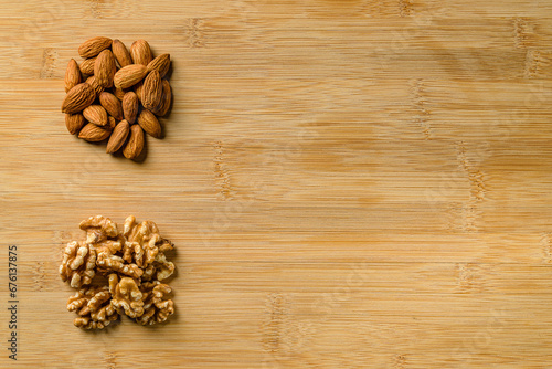 Raw almonds and walnut halves on the wooden cutting board backgr © Vadim