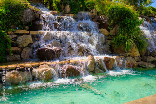 Artificial waterfall. Popular place in hot weather. Background with selective focus and copy space