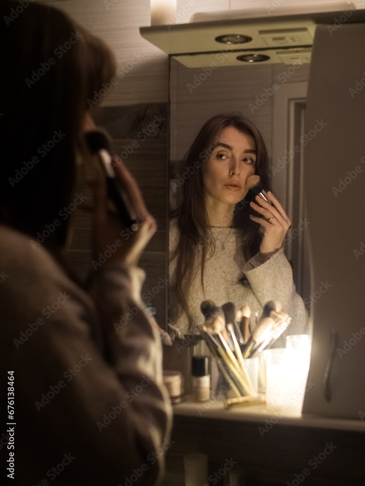 young woman doing make-up in a bathroom without electricity by candlelight