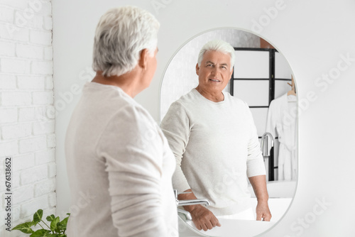 Senior man looking in mirror at home