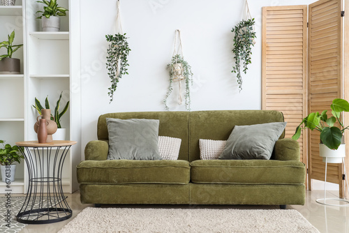 Interior of light living room with green sofa and houseplants