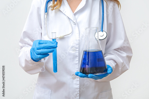 Fototapeta Naklejka Na Ścianę i Meble -  Female lab worker holding test tube and conical flask with sample on white background