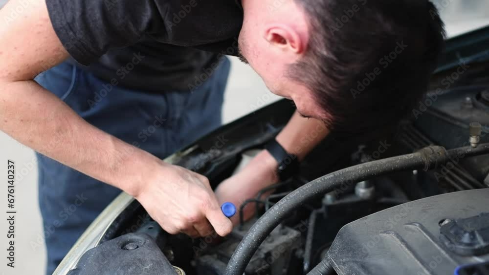 A young guy unscrews a car headlight bulb with a screwdriver. A young guy unscrews a car headlight bulb with a screwdriver.