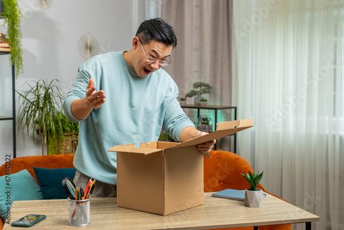 Bilde på lerret Happy Asian mature man unpacking delivery parcel at home