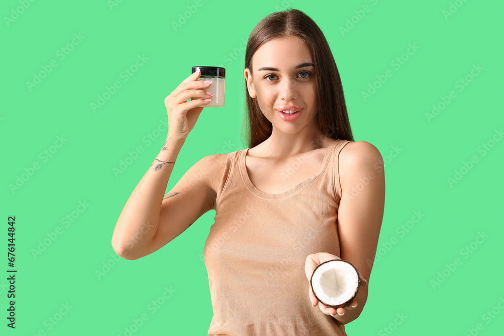 Beautiful young woman with coconut and jar of oil on green background Beautiful young woman with coconut and jar of oil on green background