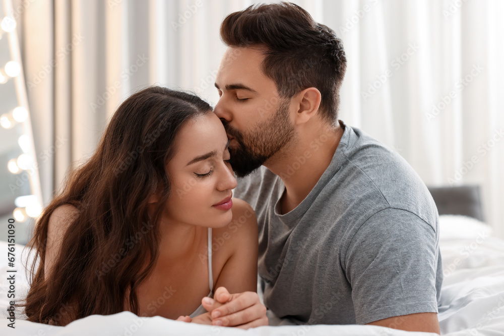 Man kissing his girlfriend on bed indoors Man kissing his girlfriend on bed indoors