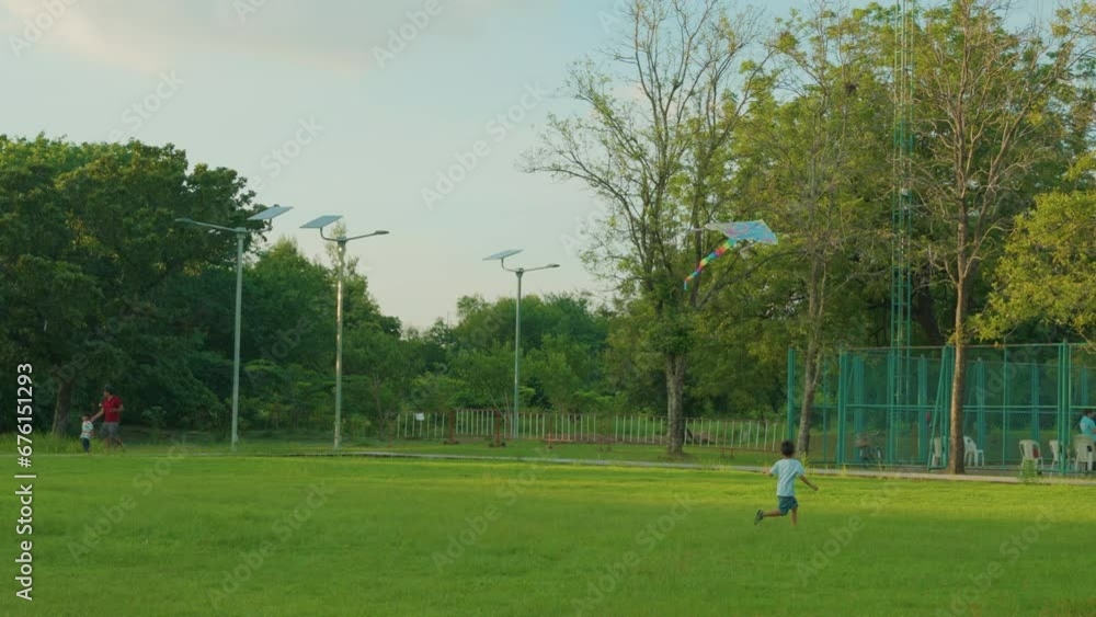 Little asian kindergarten boy running with kite in the green grass field on summer day in the city park Little asian kindergarten boy running with kite in the green grass field on summer day in the city park