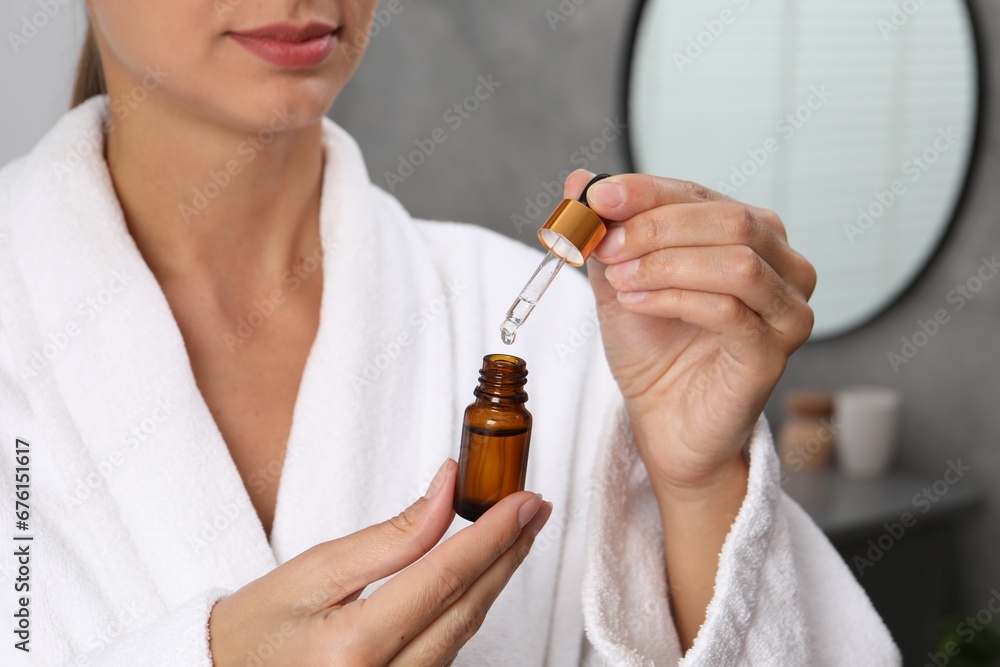 Woman with bottle of cosmetic serum and dropper indoors, closeup Woman with bottle of cosmetic serum and dropper indoors, closeup