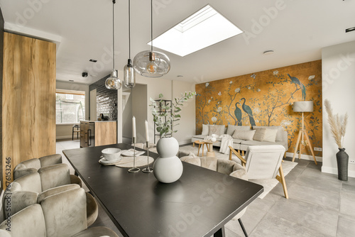 a living room with an orange mural on the wall and two white chairs in the center of the room there is a black table photo