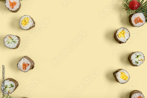 Christmas composition with tasty sushi rolls and fir tree branch on beige background