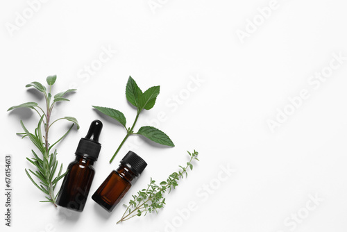 Bottles of essential oils and different herbs on white background, flat lay. Space for text