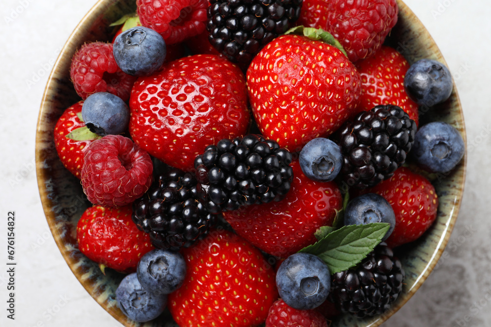 Obraz premium Different fresh ripe berries in bowl on table, top view