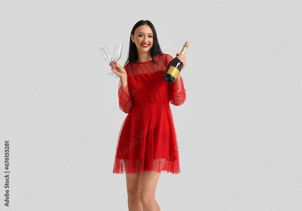 Beautiful young woman with glasses and bottle of champagne on white background Beautiful young woman with glasses and bottle of champagne on white background