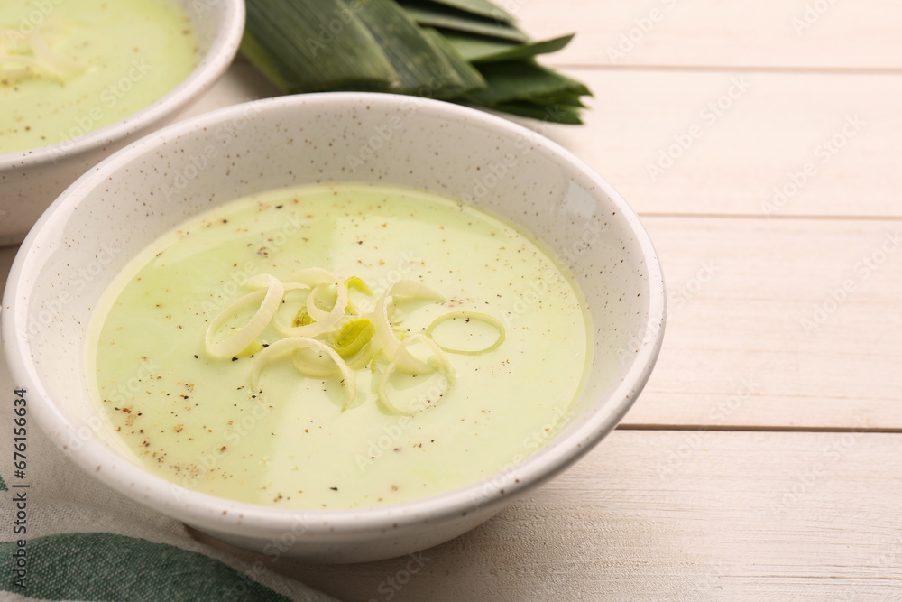 Bowl of tasty leek soup on white wooden table, closeup. Space for text Bowl of tasty leek soup on white wooden table, closeup. Space for text
