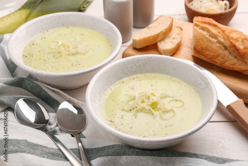 Bowls of tasty leek soup on white wooden table, closeup