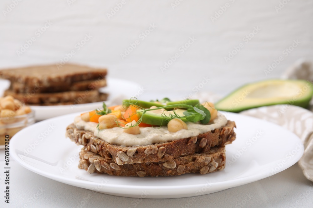 Tasty vegan sandwich with avocado, chickpeas and bell pepper on white table, closeup