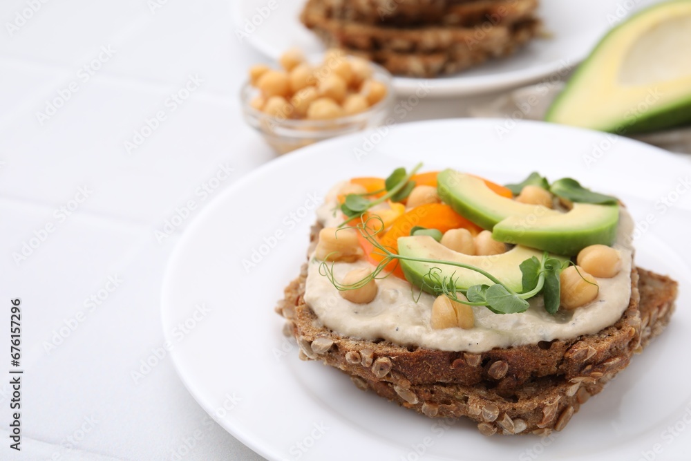 Tasty vegan sandwich with avocado, chickpeas and bell pepper on white table, closeup