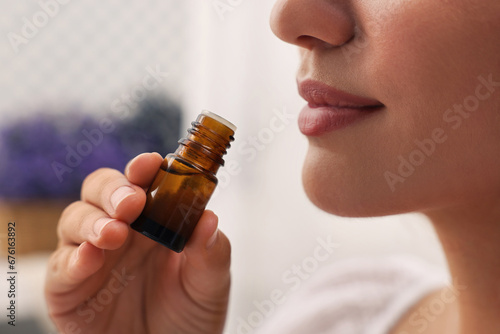 Tableau sur toile Woman with bottle of essential oil indoors, closeup