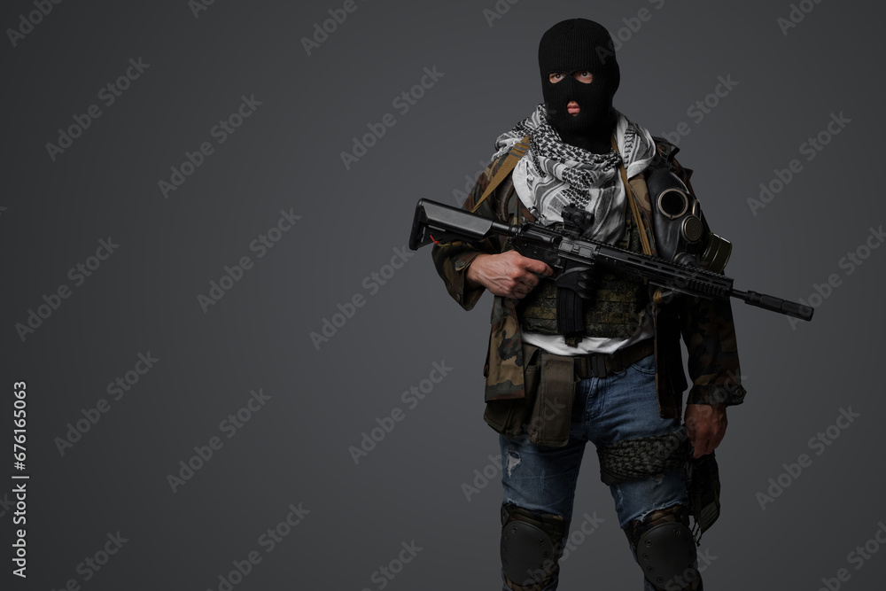 A Middle Eastern radical soldier dressed in a black balaclava and camouflaged field uniform, armed with a rifle, against a gray background A Middle Eastern radical soldier dressed in a black balaclava and camouflaged field uniform, armed with a rifle, against a gray background