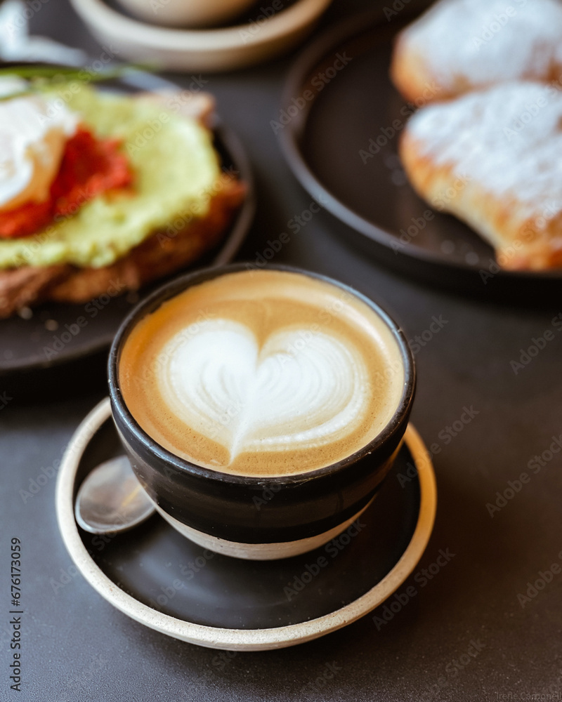 Cafe con dibujo de corazon en una taza y plato negro, con galletas en el desayuno Cafe con dibujo de corazon en una taza y plato negro, con galletas en el desayuno