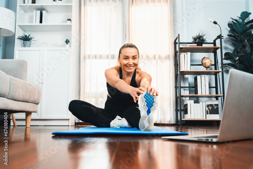 Active and fit senior woman warmup and stretching before home exercising routine at living room while watching online fitness video. Healthy lifestyle concept after retirement for pensioner. Clout